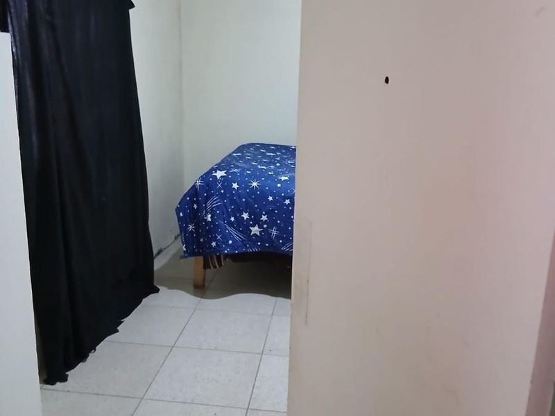 A compact bedroom featuring tiled flooring and a ventilation grille, requiring cosmetic updates to improve its overall condition and appeal.