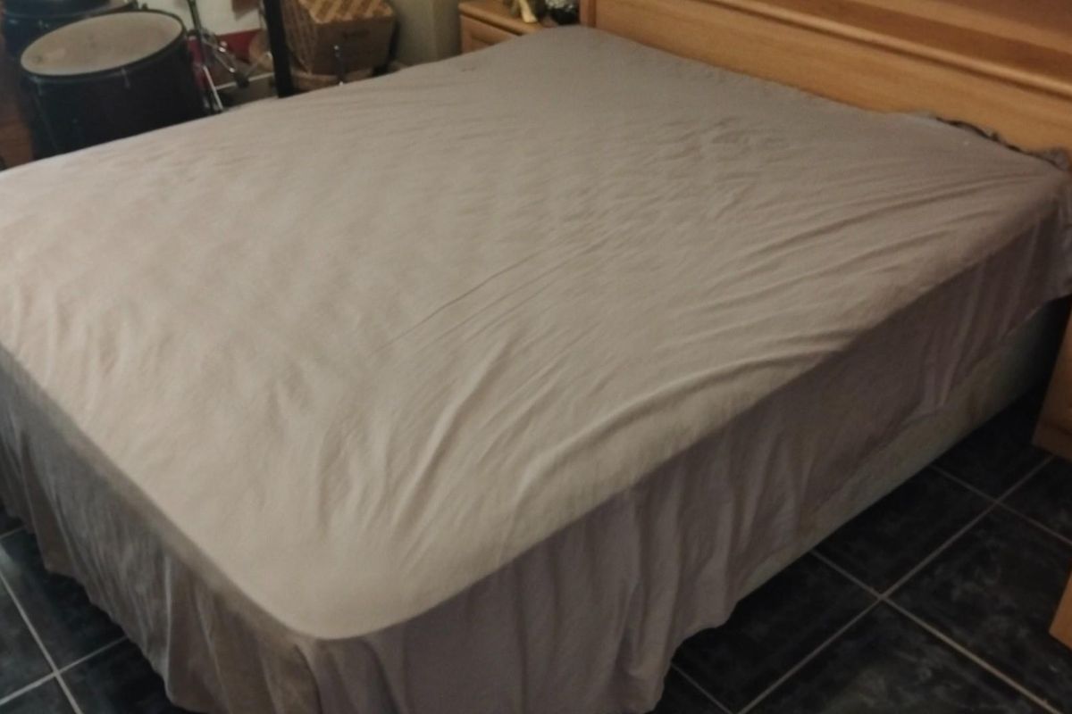 A bedroom featuring dark tiled flooring and a built-in wooden headboard.