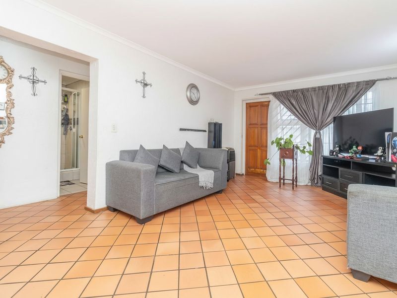 A spacious living room featuring traditional terracotta tiled flooring, coved ceilings, and direct access to an adjacent room.
