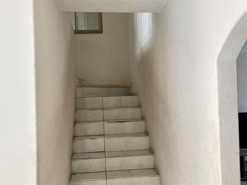 A simple interior staircase featuring tiled steps and an arched entryway, leading to an upper level.