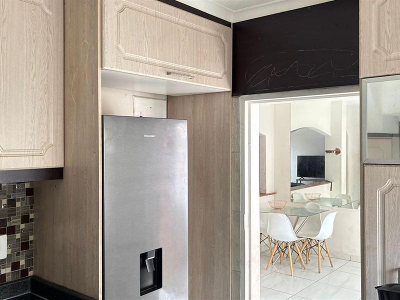Kitchen featuring light wood-look cabinetry, mosaic tile backsplash, and stone countertops, with a direct view into the adjacent dining area.
