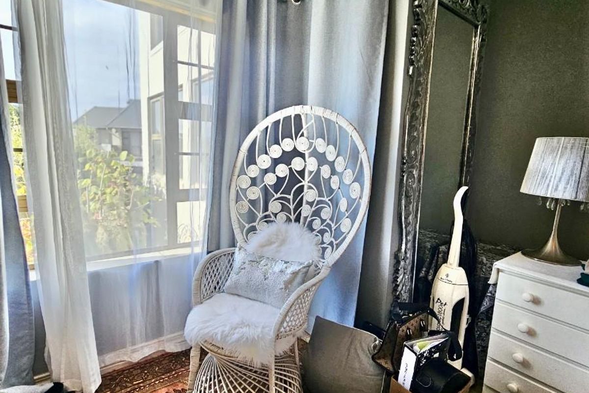 A corner bedroom space featuring crown molding, large windows with curtains, and dark-toned walls.
