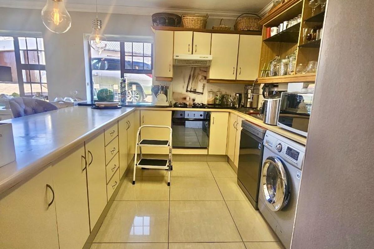 A functional kitchen featuring tiled flooring, ample cabinetry, a built-in oven with extractor fan, and integrated space for laundry appliances.