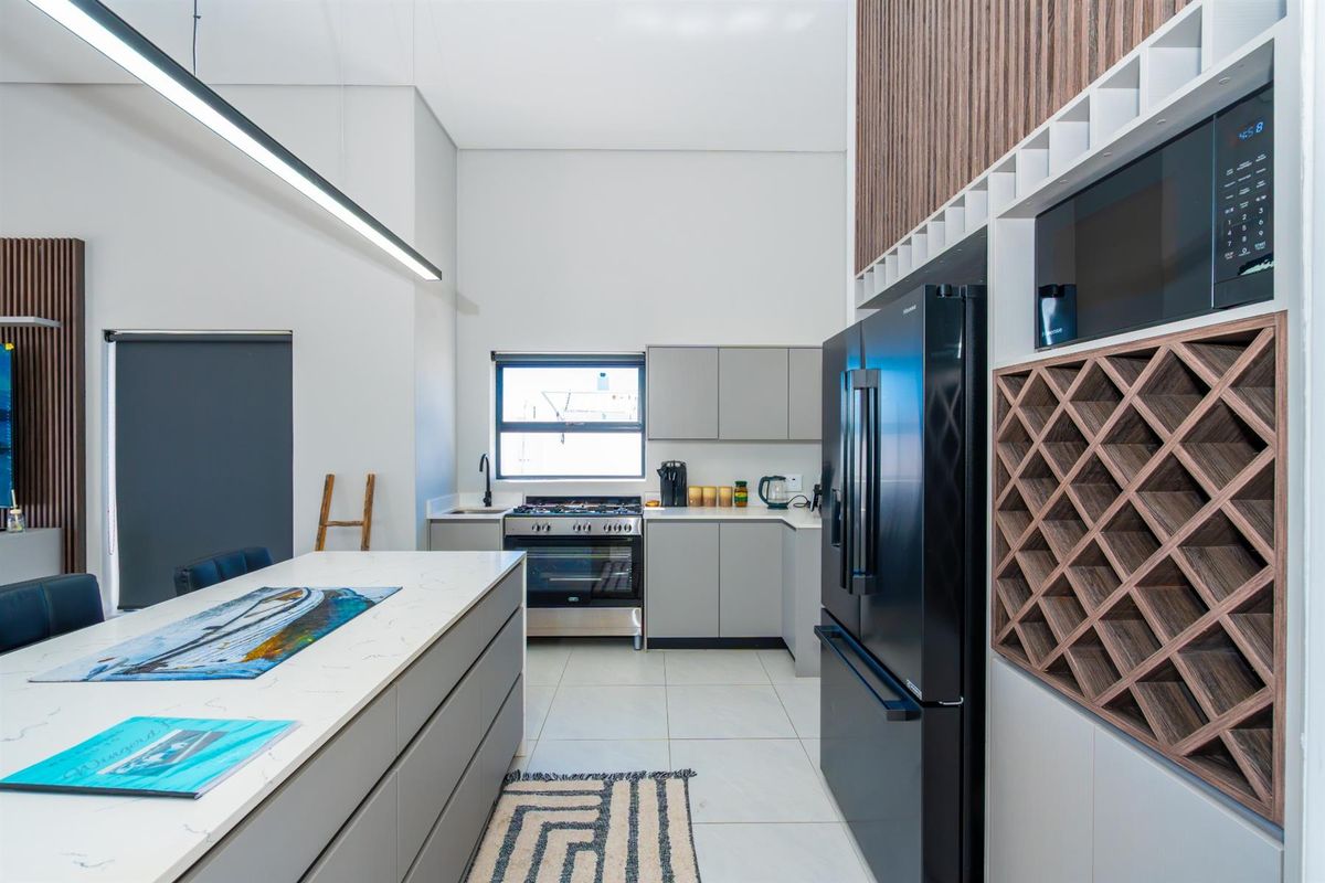 Modern kitchen featuring a central island with stone countertop, sleek cabinetry, built-in wine rack, and high-end stainless steel gas stove.