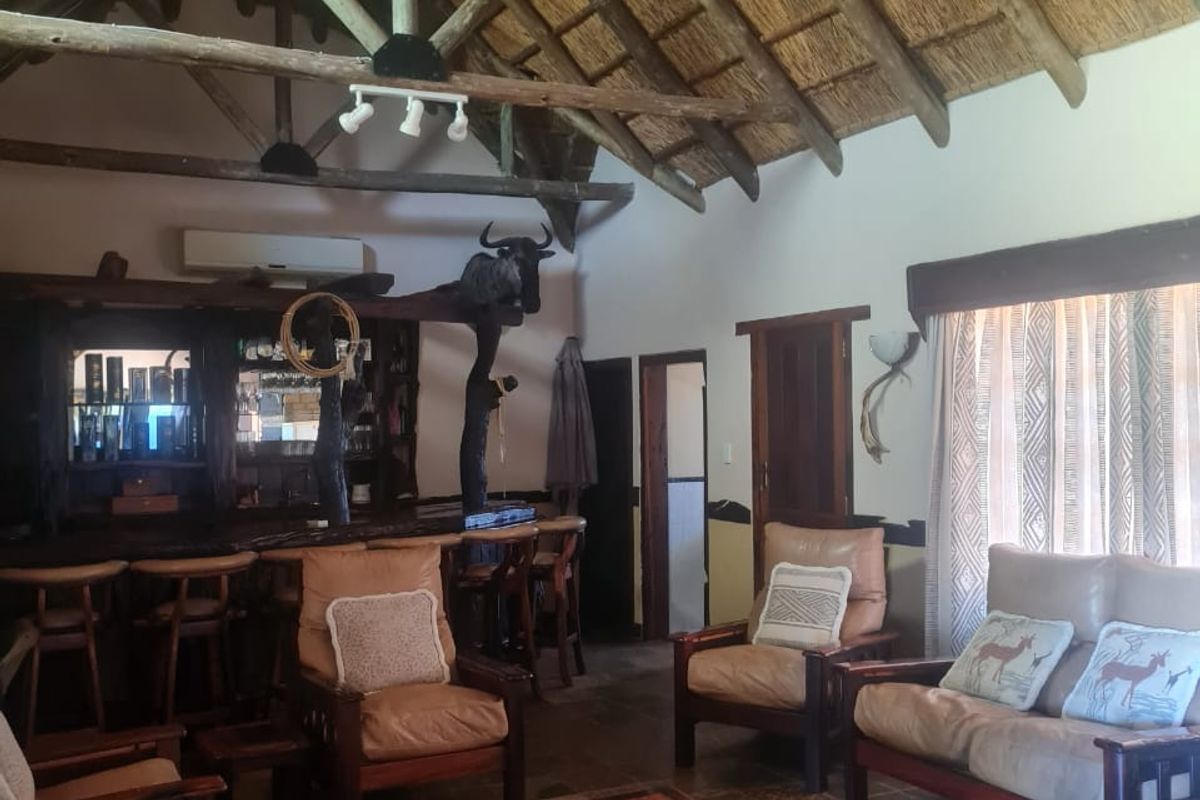 Spacious living area featuring a high vaulted thatched ceiling with exposed timber trusses, slate tile flooring, and a built-in wooden bar counter.