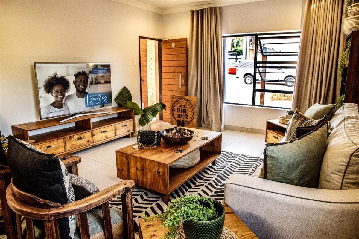 A well-maintained living room featuring tiled flooring, a large window, and a solid timber entrance door, creating a warm and inviting atmosphere.