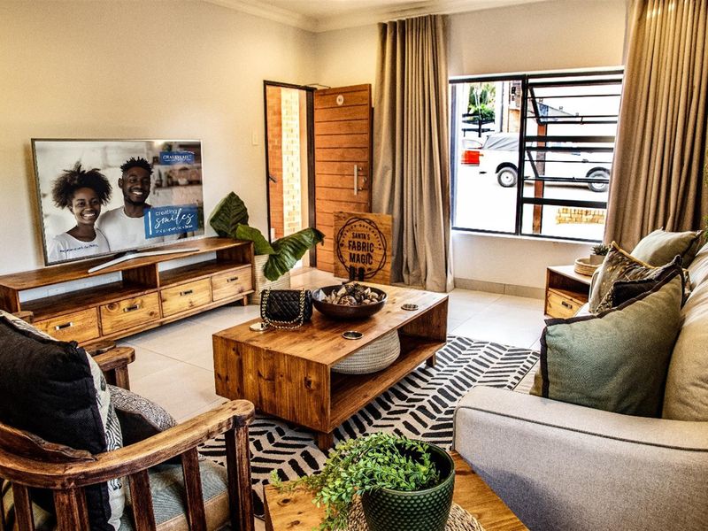 A well-maintained living room featuring tiled flooring, a large window, and a solid timber entrance door, creating a warm and inviting atmosphere.