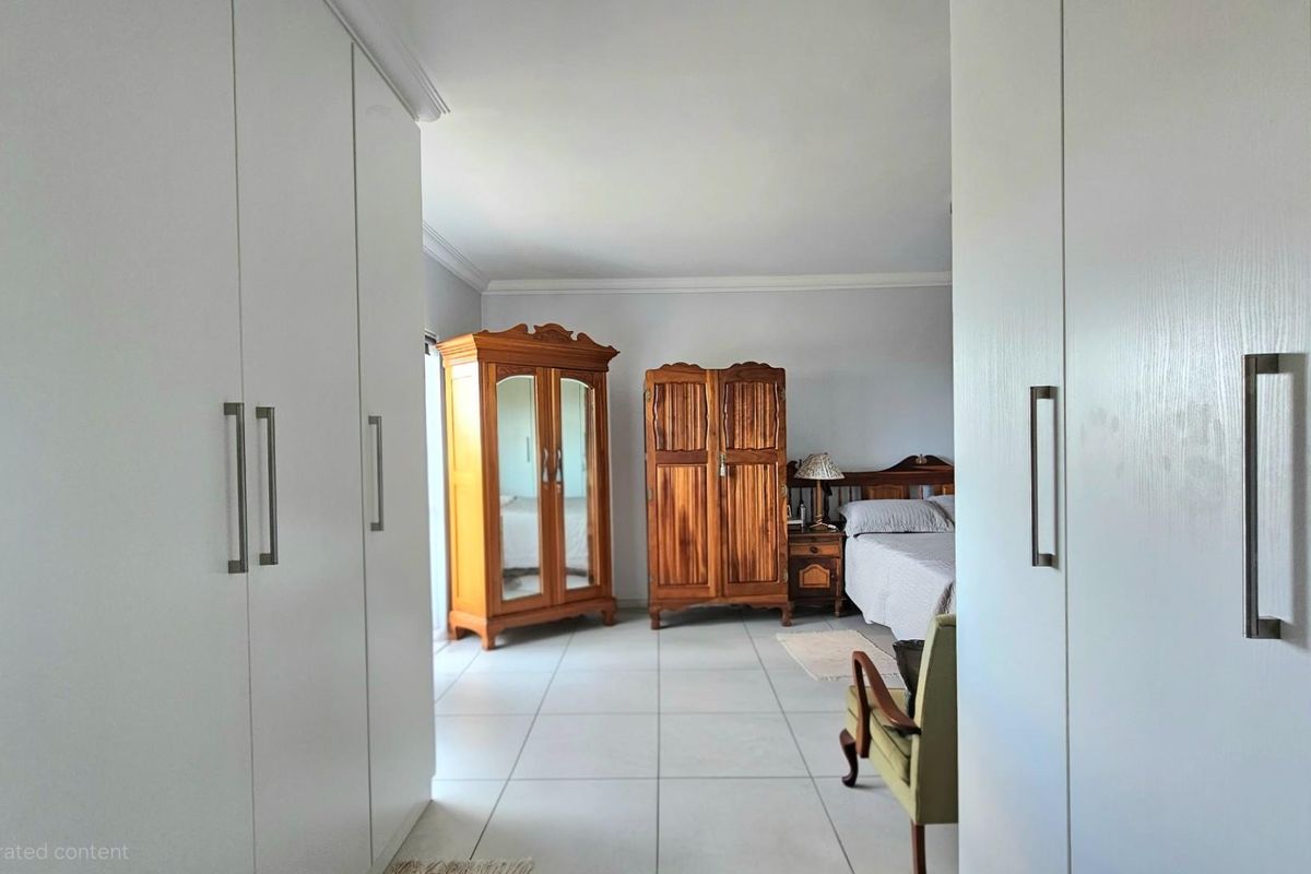 Spacious bedroom featuring built-in floor-to-ceiling wardrobes and neutral tiled flooring, offering a clean and functional layout.