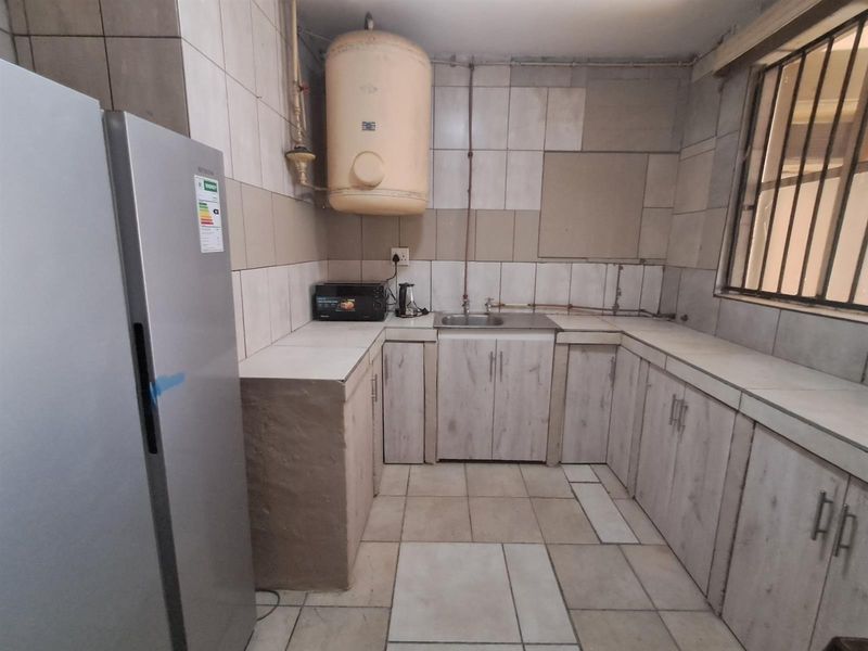 A functional kitchen featuring tiled walls, built-in cabinetry, a stainless steel sink, and a wall-mounted water heater.
