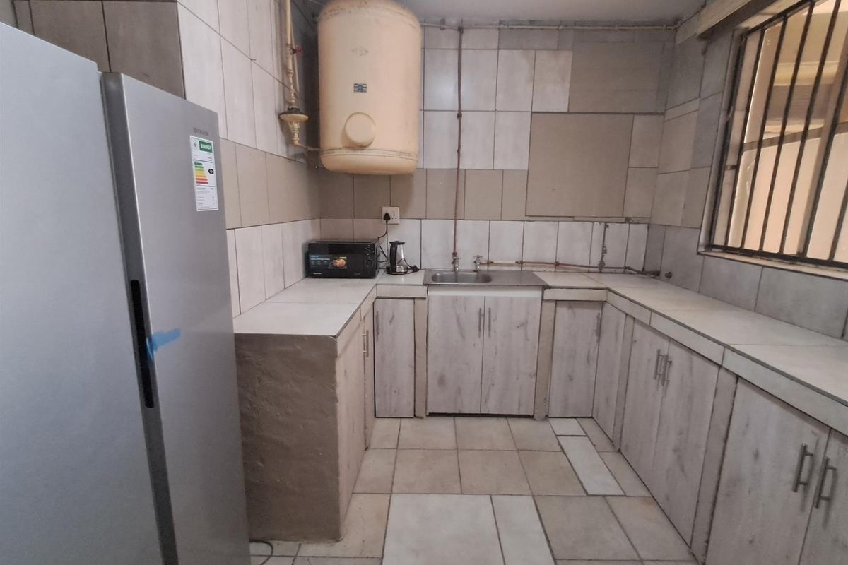 A functional kitchen featuring tiled walls, built-in cabinetry, a stainless steel sink, and a wall-mounted water heater.