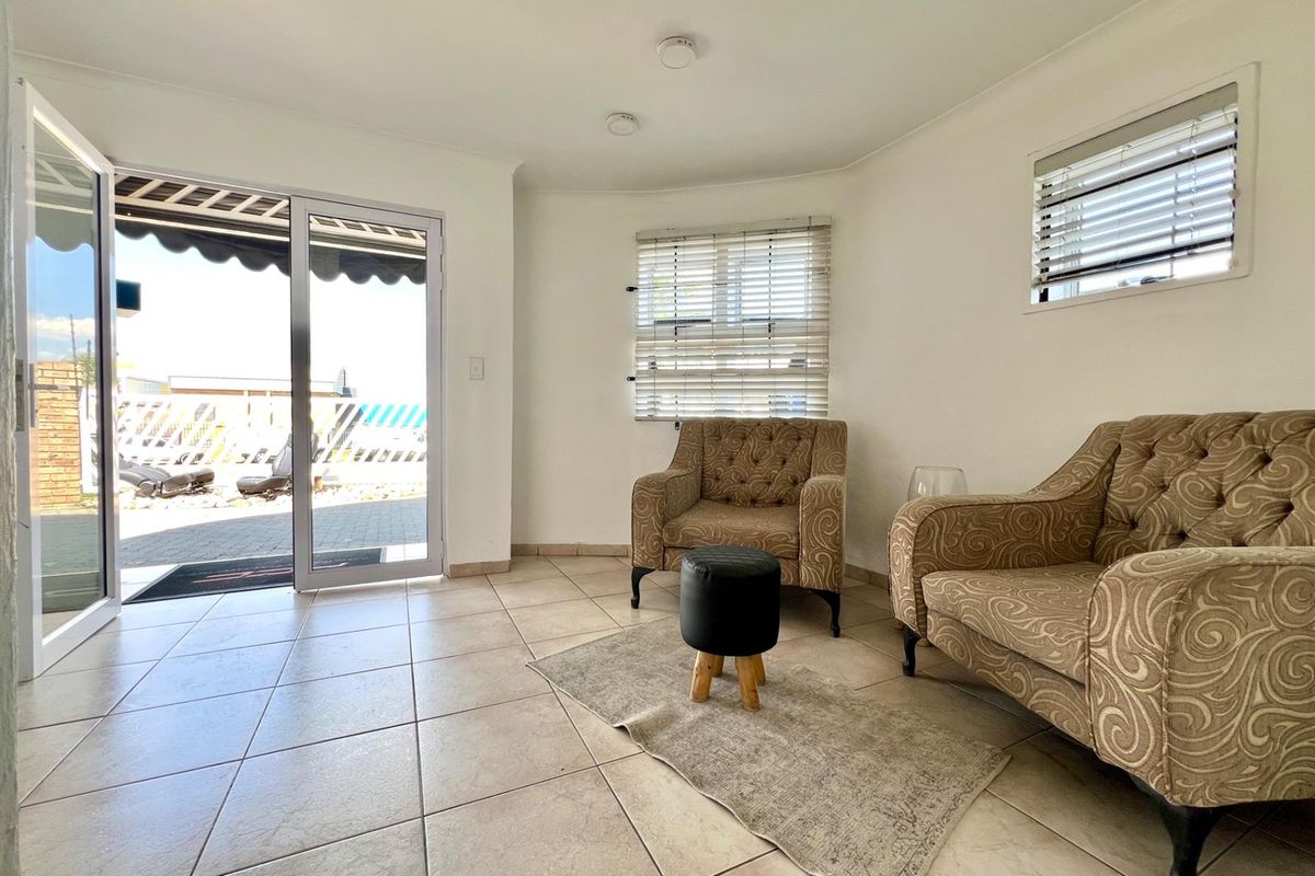 A bright living area featuring tiled flooring, recessed ceiling lighting, and sliding glass doors providing direct access to an outdoor patio space.