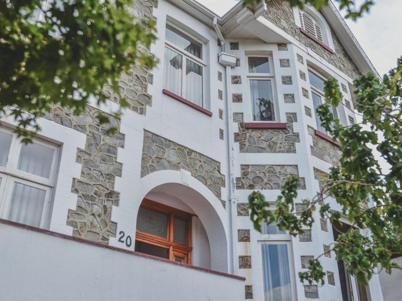 A charming commercial building facade featuring traditional stone masonry, arched entrance, and classic casement windows with painted brick detailing.