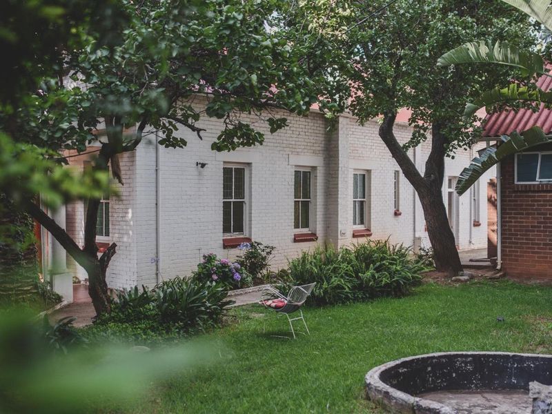 A view of the rear exterior featuring a painted brick facade, sash windows, and a landscaped garden area with a concrete feature.