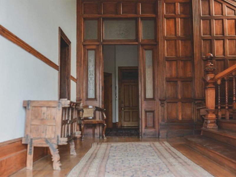 Grand entrance hall featuring intricate timber wall paneling, a classic wooden staircase, and original hardwood flooring, showcasing traditional architectural craftsmanship.