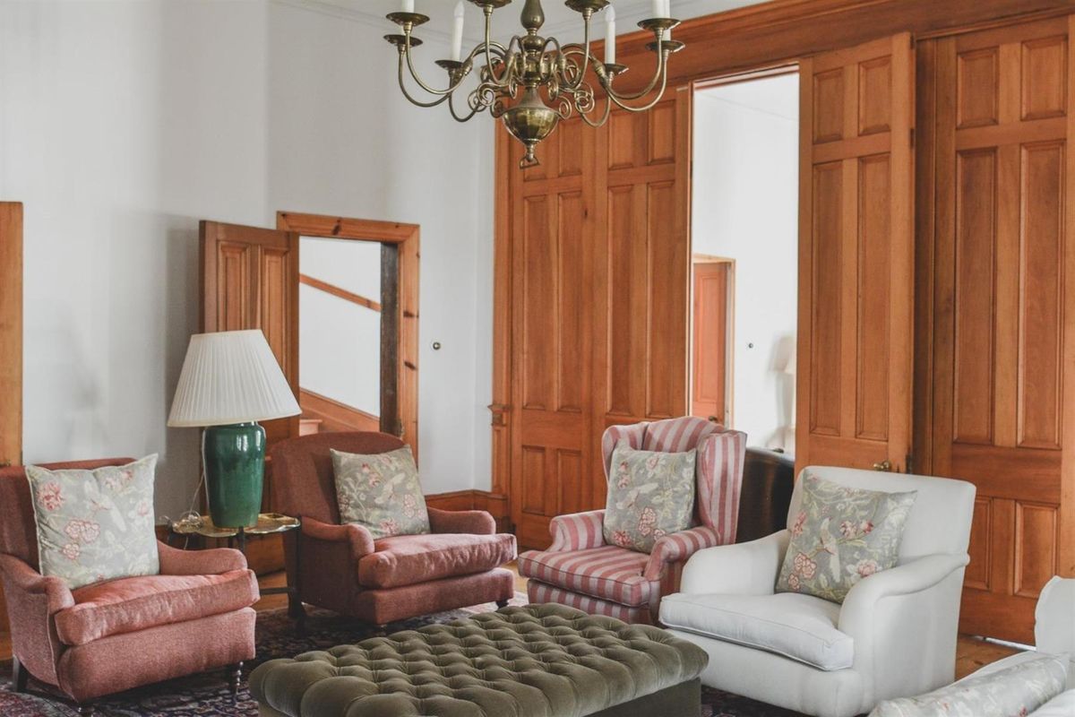 A classic living room featuring elegant timber paneling, solid wood doors, and a traditional brass chandelier, showcasing high-quality architectural craftsmanship.