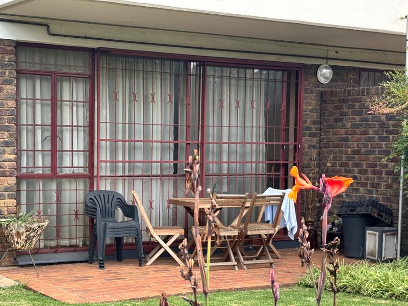 A ground floor patio area featuring brick paving, sliding doors with security gates, and an exterior wall light, providing direct access to the garden.