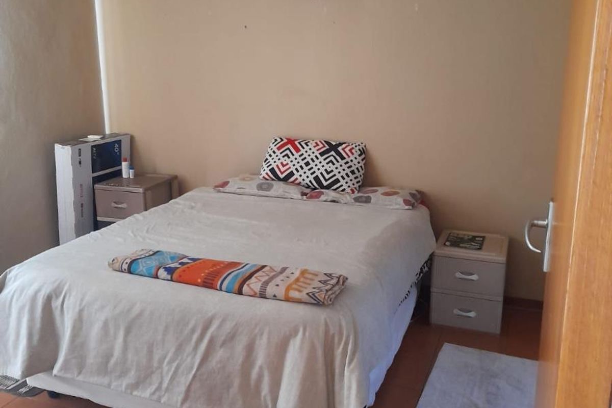 A functional bedroom featuring tiled flooring and neutral wall finishes, providing a simple and practical living space.