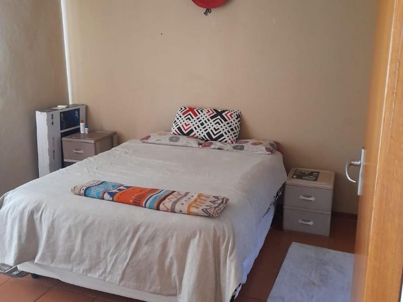 A functional bedroom featuring tiled flooring and neutral wall finishes, providing a simple and practical living space.