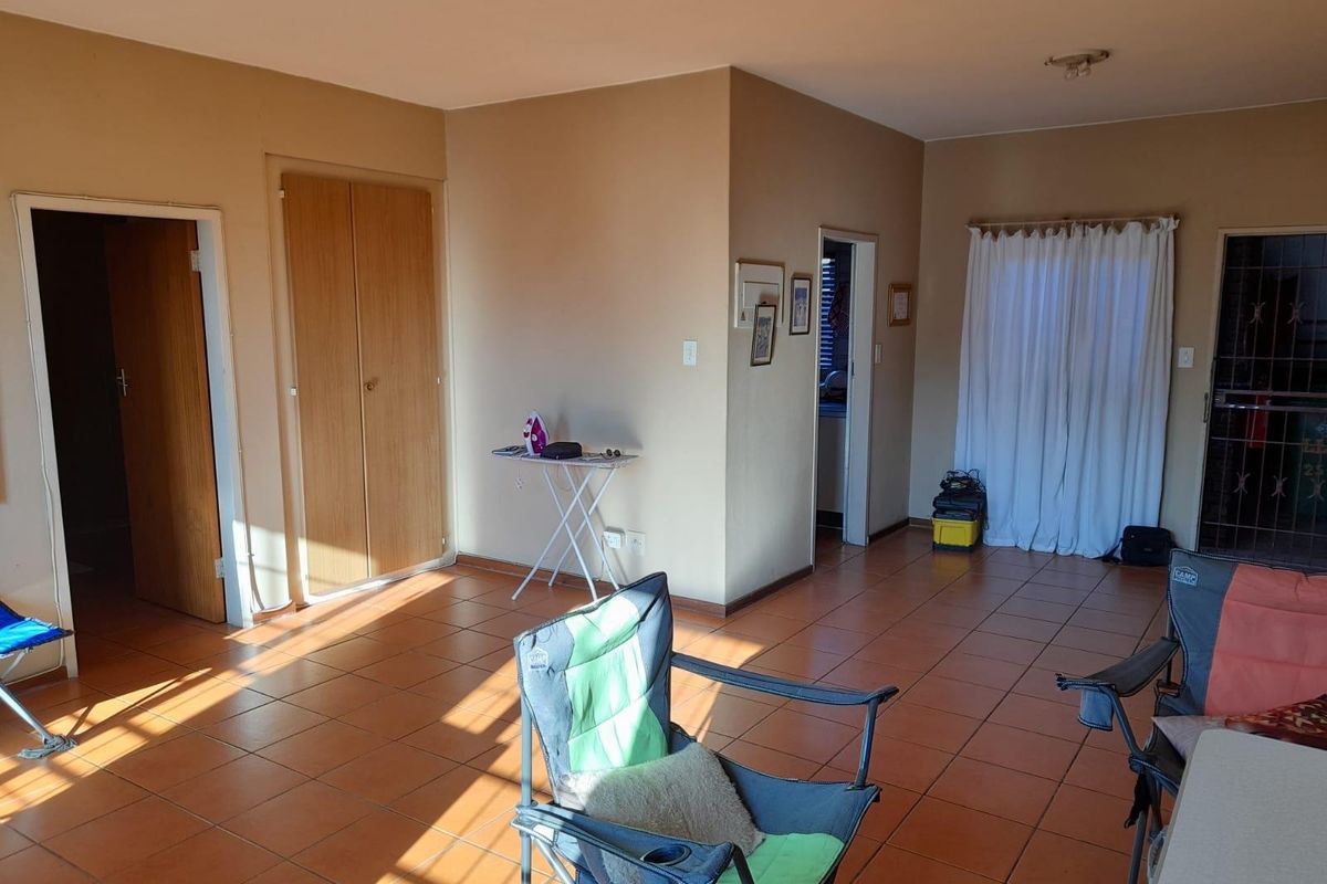 A spacious living area featuring neutral wall tones, ceramic floor tiles, and built-in storage cupboards, offering a versatile layout for various furniture arrangements.