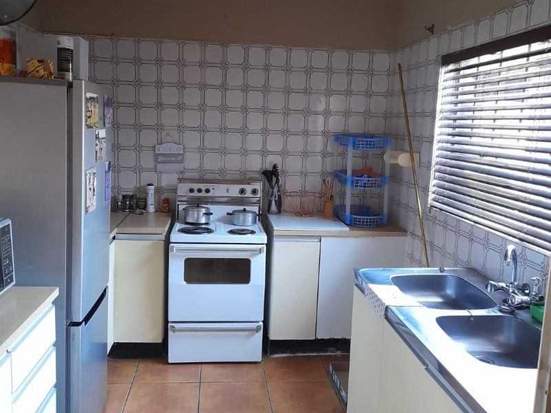 A functional kitchen featuring a freestanding stove, double basin sink, laminate countertops, and tiled finishes throughout.