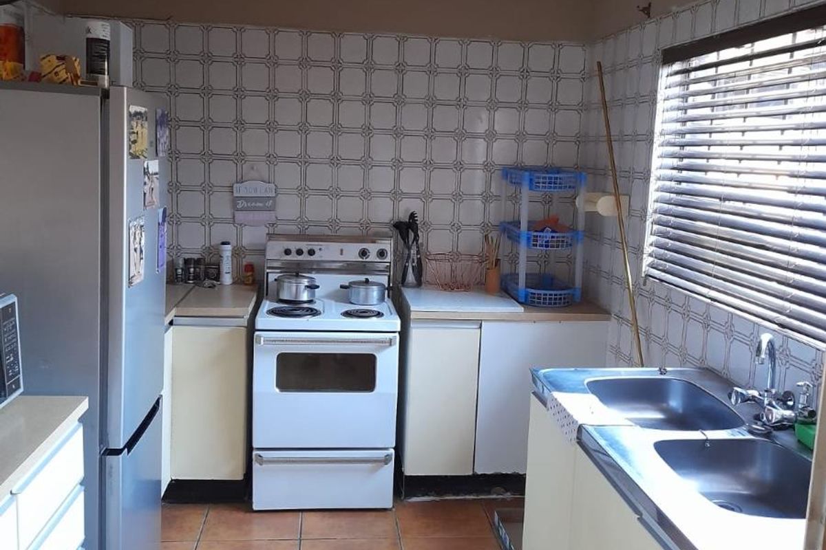 A functional kitchen featuring a freestanding stove, double basin sink, laminate countertops, and tiled finishes throughout.