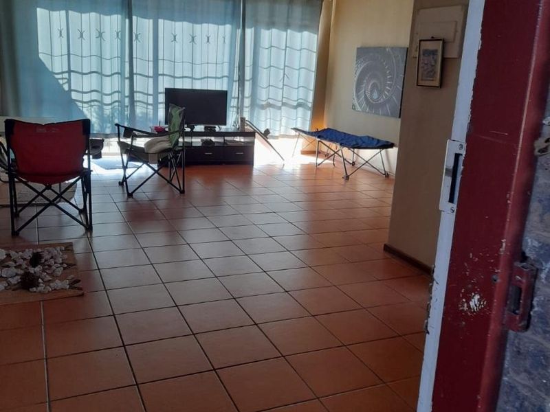 Spacious living area featuring large sliding glass doors that provide ample natural light and access to the exterior, finished with durable floor tiles.