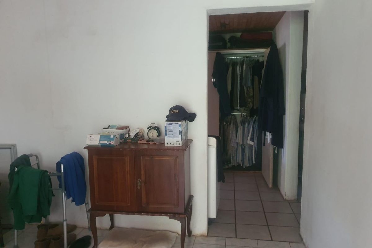 A bedroom interior featuring tiled flooring and an open doorway leading to a walk-in closet area with built-in hanging rails.