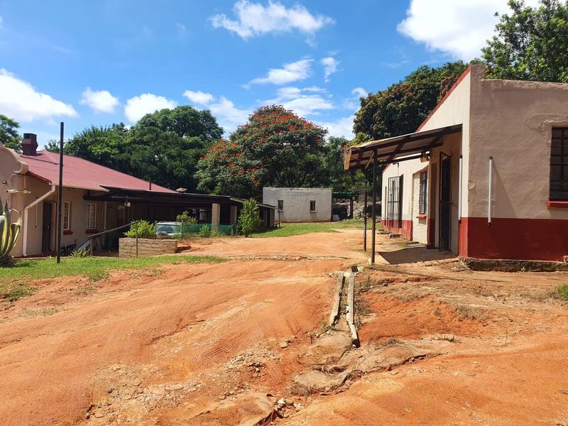 Exterior view of farm outbuildings featuring traditional architecture, metal roofing, and a large unpaved courtyard area.