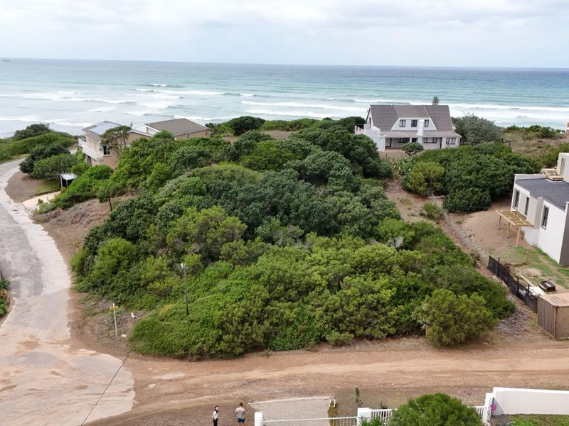 An aerial view of a vacant residential plot featuring dense coastal vegetation and proximity to the ocean.