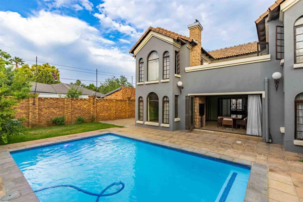 Rear view of the property featuring a swimming pool, paved patio area, and access to the interior living space through folding doors.