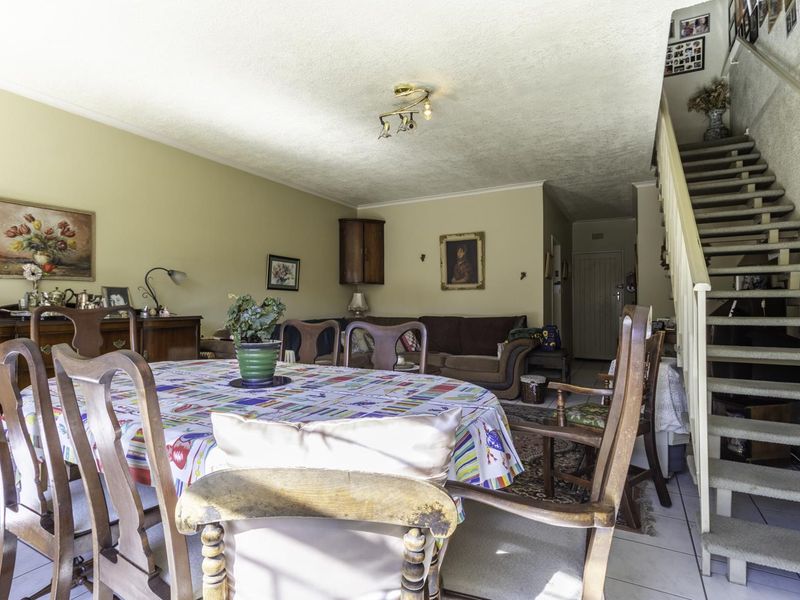 Open plan living and dining area featuring tiled flooring and a staircase leading to the upper level.
