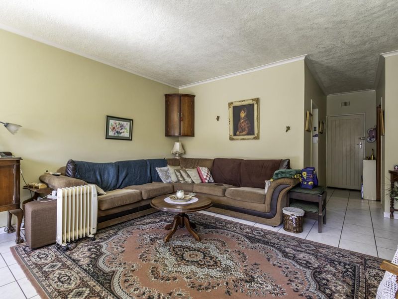 A living room featuring tiled flooring, cornicing, and a built-in corner wall cabinet, offering a functional space with potential for modernization.