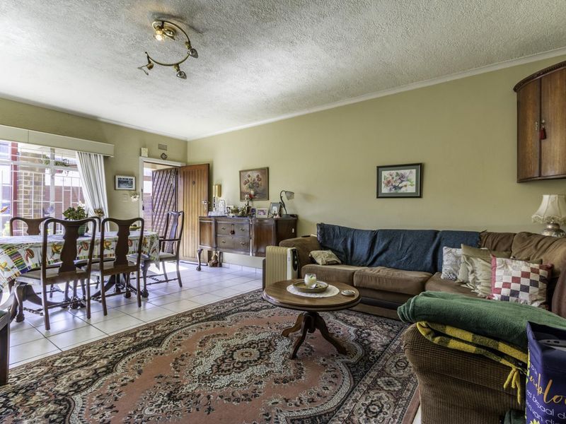 Open plan living and dining area featuring tiled flooring, textured ceilings, and direct access to an outdoor patio through a sliding glass door.