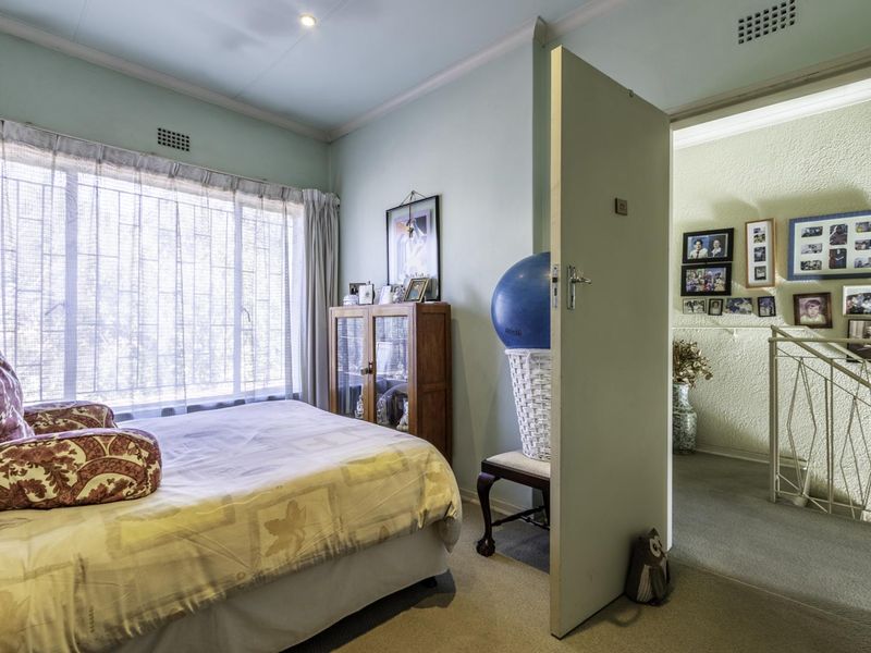 A bedroom featuring carpeted flooring, coved ceiling cornices, and a built-in ceiling vent, with an open doorway leading to a hallway area.