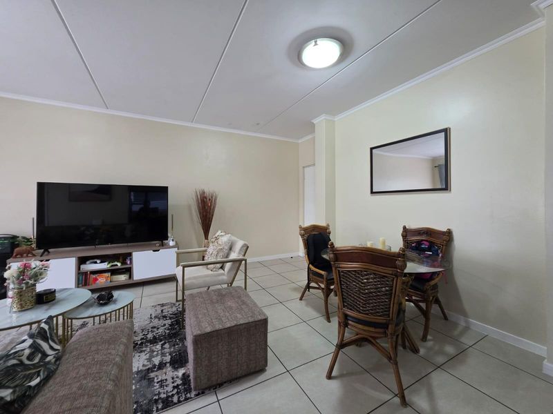 An open-plan living and dining area featuring neutral tiled flooring and a coved ceiling, providing a functional and versatile space for daily living.