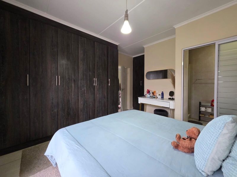 Spacious bedroom featuring extensive dark wood built-in cupboards and direct access to an en-suite bathroom.