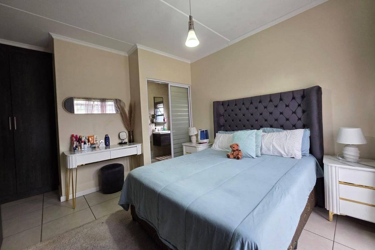 A well-maintained bedroom featuring tiled flooring, a built-in wardrobe, and an en-suite bathroom access via a sliding door.