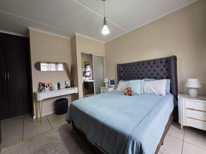 A well-maintained bedroom featuring tiled flooring, a built-in wardrobe, and an en-suite bathroom access via a sliding door.