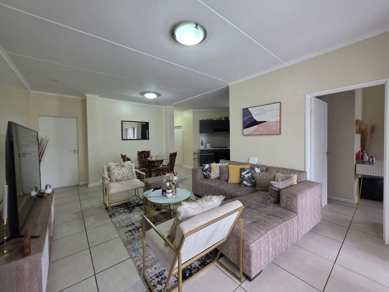 Open-plan living and dining area featuring neutral tiled flooring and direct access to a compact kitchen space.