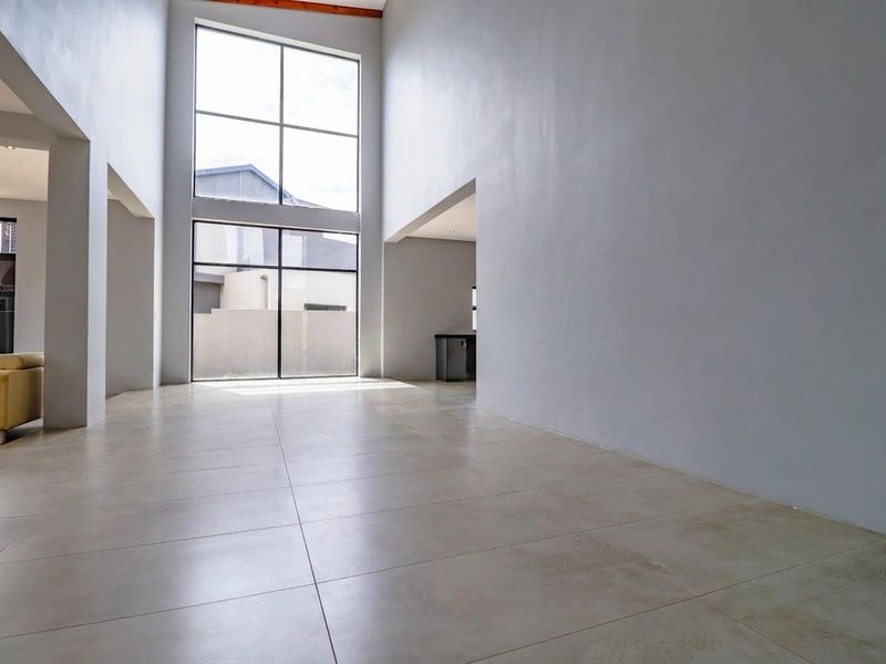 Spacious, light-filled living area featuring double-volume ceilings, large windows, and modern porcelain tile flooring.