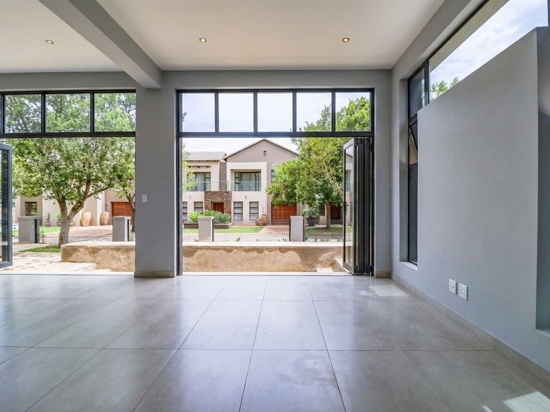 Spacious, light-filled living area featuring large format floor tiles, recessed lighting, and expansive aluminium stackable doors opening to a private outdoor space.