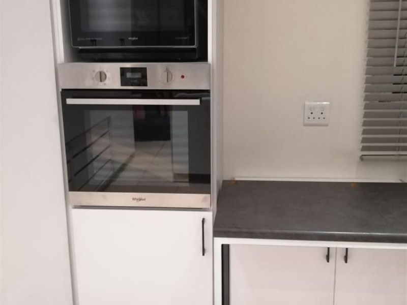 A modern kitchen section featuring built-in cabinetry, a dark countertop, and integrated Whirlpool oven and microwave appliances.