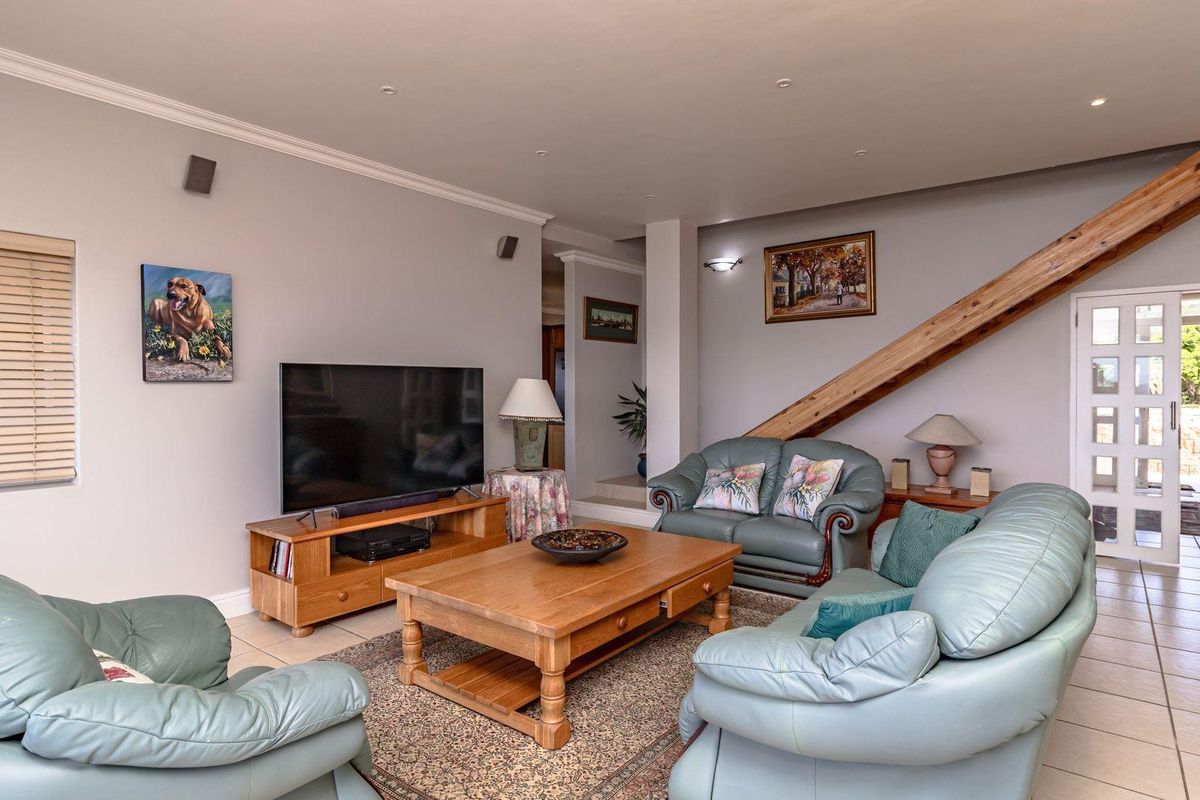 Spacious living room featuring tiled flooring, recessed ceiling lighting, and a wooden staircase leading to the upper level.