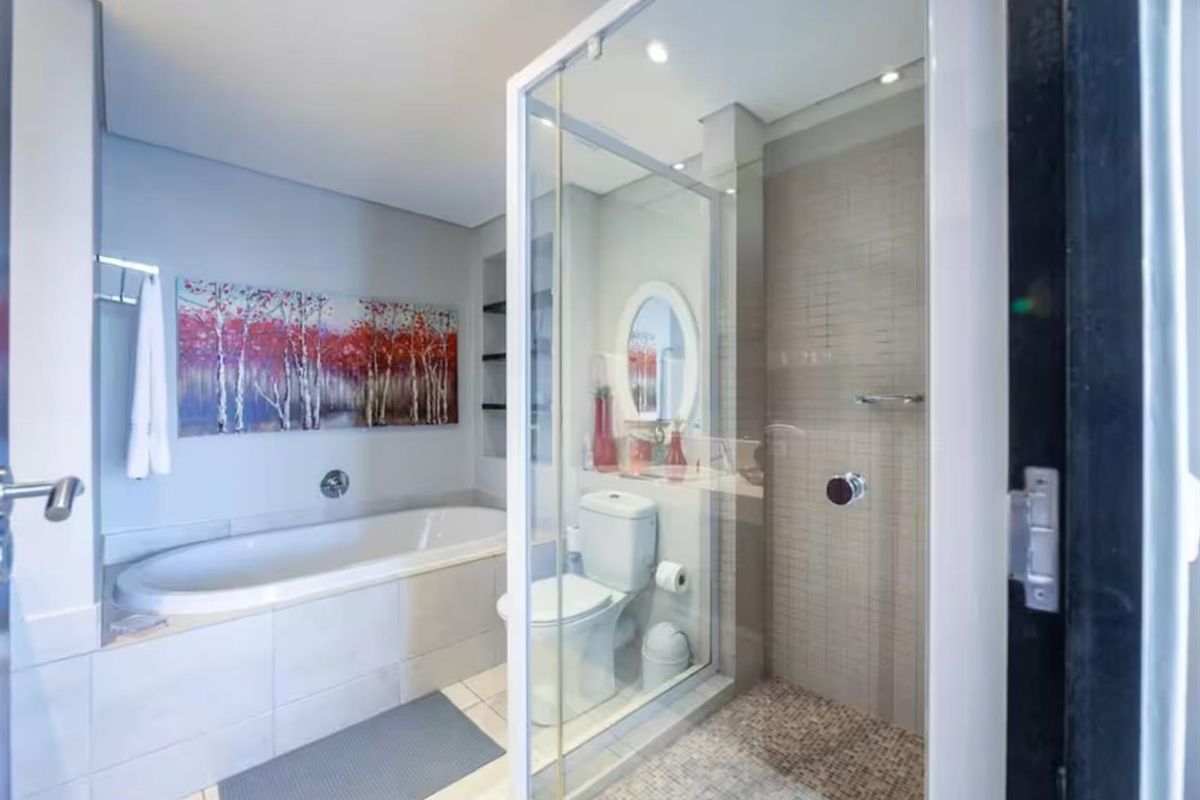 Modern bathroom featuring a built-in bathtub, a separate glass-enclosed shower with mosaic tiling, and a wall-mounted toilet with recessed lighting.