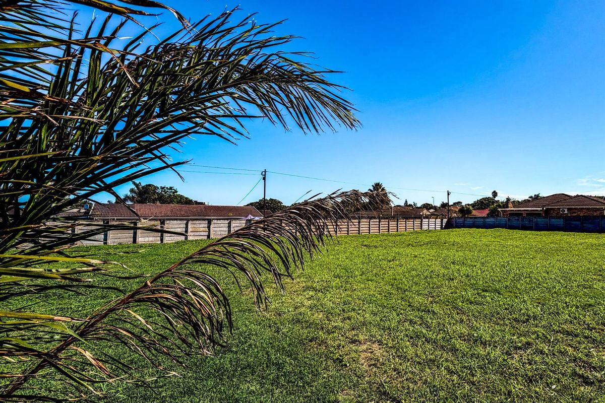 A view of a vacant residential plot featuring a well-maintained grass lawn and perimeter boundary walling.