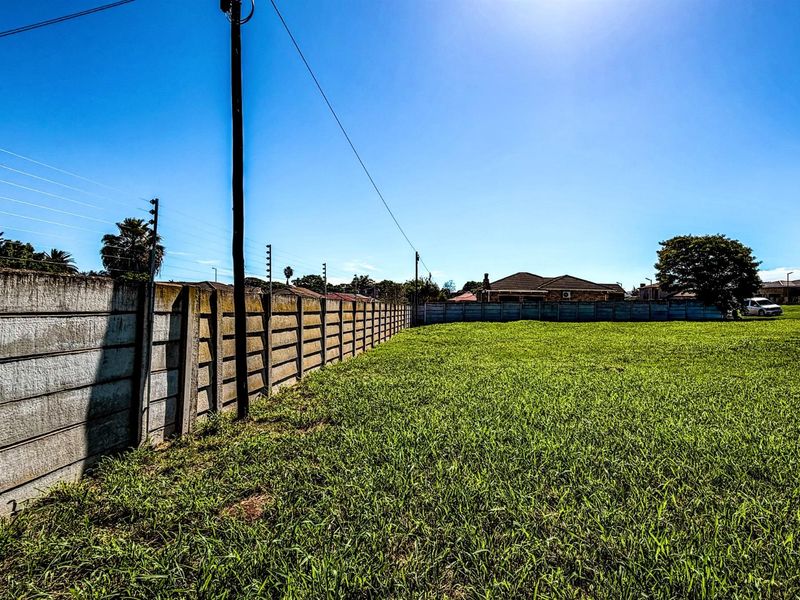 A vacant residential plot featuring a perimeter concrete boundary wall with electric fencing, offering a clear space ready for development.