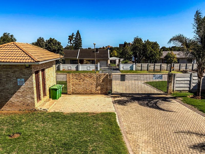 View of the property entrance featuring a brick-built guard house, paved driveway, and secure metal gate access.