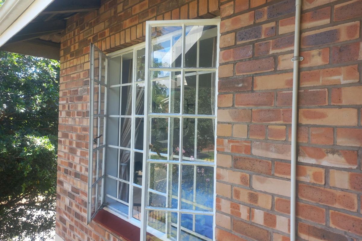 Exterior view of the apartment featuring face brick facade and white steel-framed casement windows.