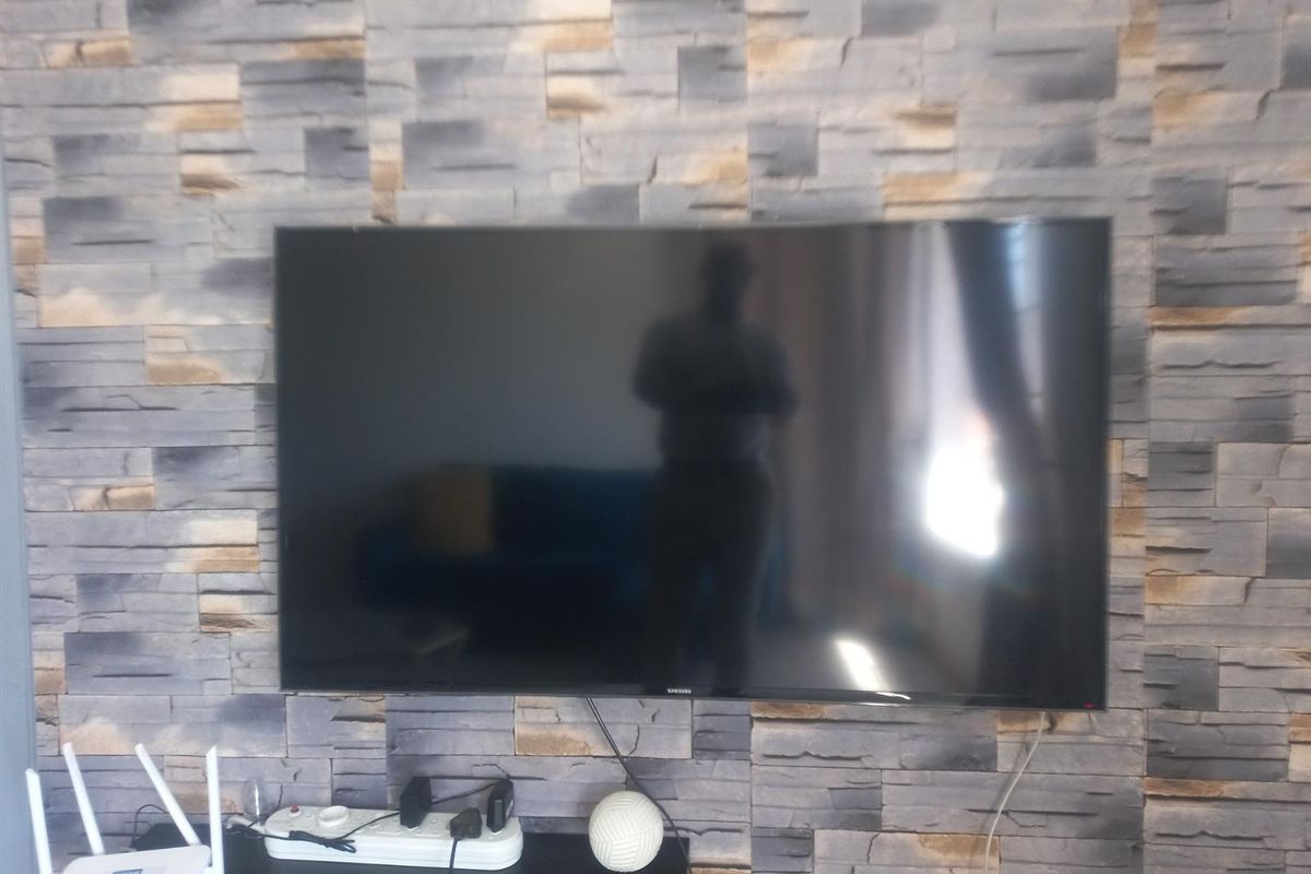 A living room wall featuring decorative stone-effect cladding with a wall-mounted television.