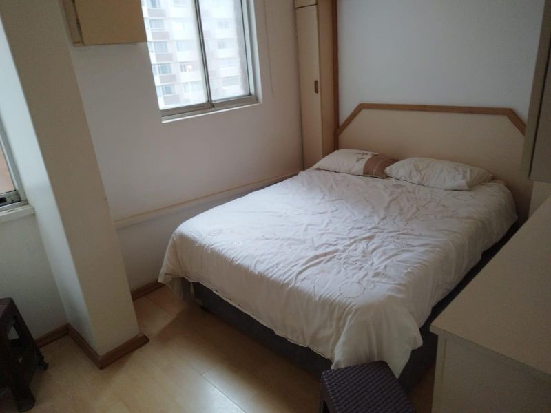 A functional bedroom featuring laminate flooring, a built-in wardrobe, and a sliding window providing natural light.
